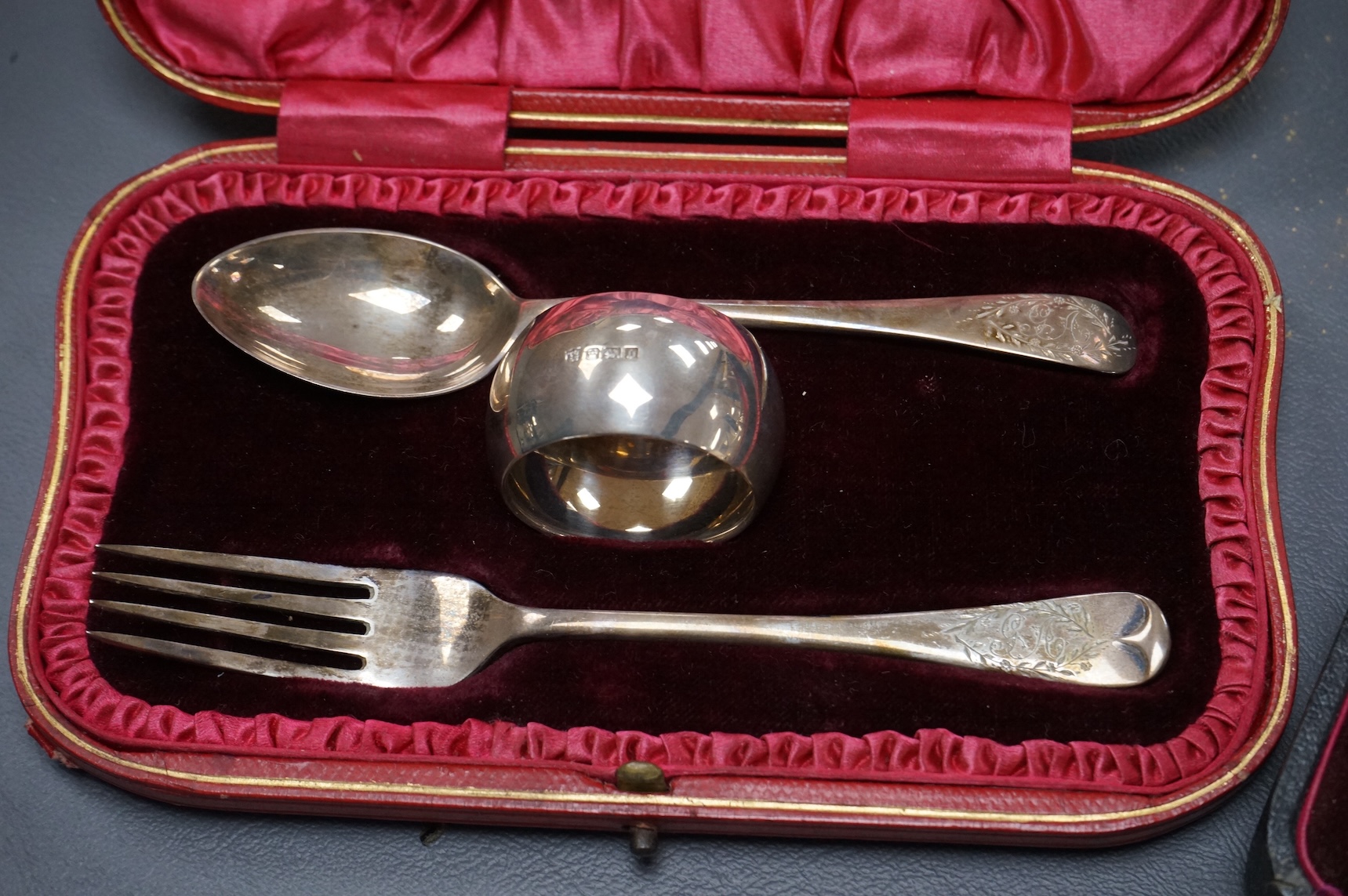Three cased silver items including an Edwardian christening trio, a pair of George V pepperettes, Birmingham, 1916 and a George V pierced silver oval mustard pot, Birmingham, 1916.